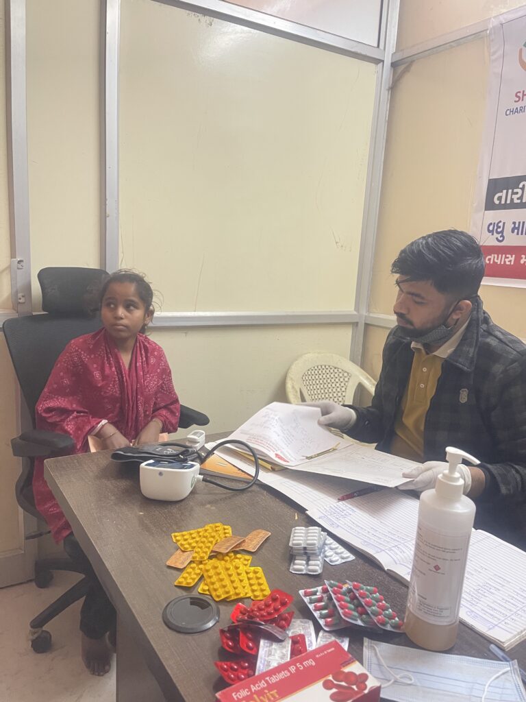 Patient receiving medical consultation during a free Sickle Cell health camp organized by Shivam Charitable Trust in Dahod.