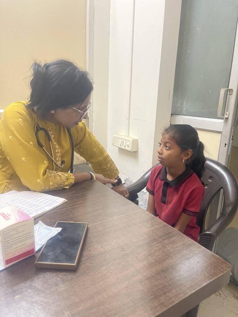 Child receiving healthcare consultation during a free Sickle Cell health camp organized by Shivam Charitable Trust in Dahod.
